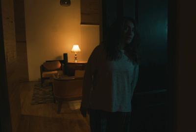 A woman in the dark looks frightened